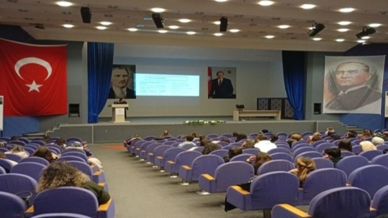 Konferans salonunda katılımcılar eğitimin konularını içeren sunumu izliyor, eğitim etkinliği.